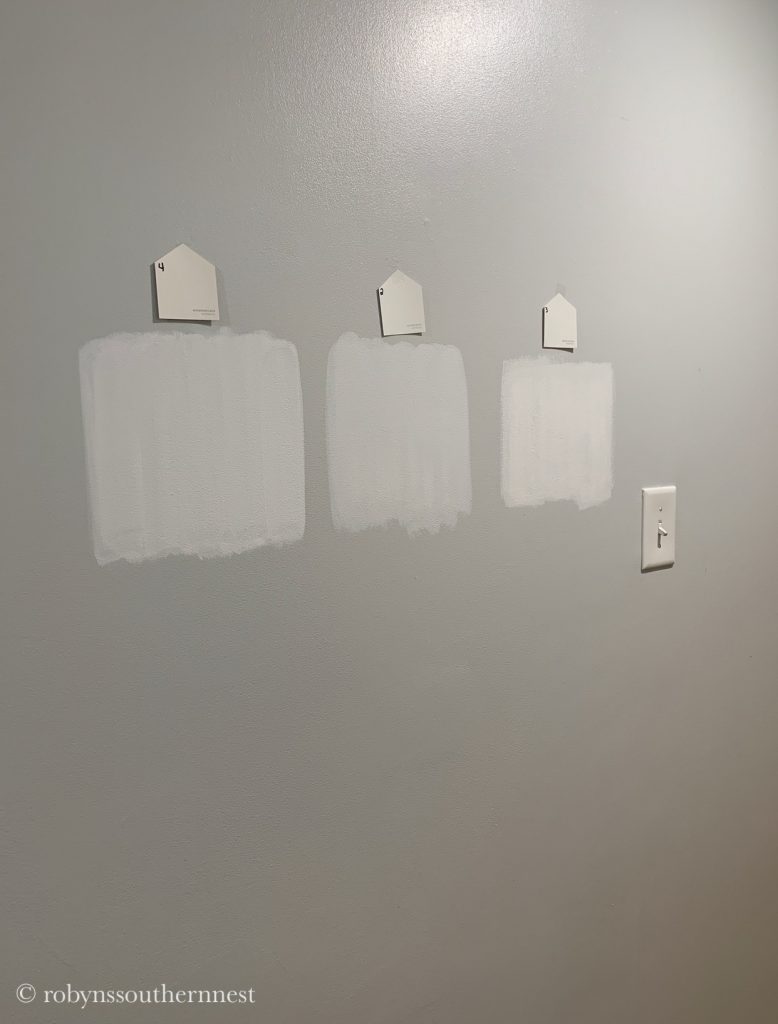 Three white paint swatches in the hallway of our basement 