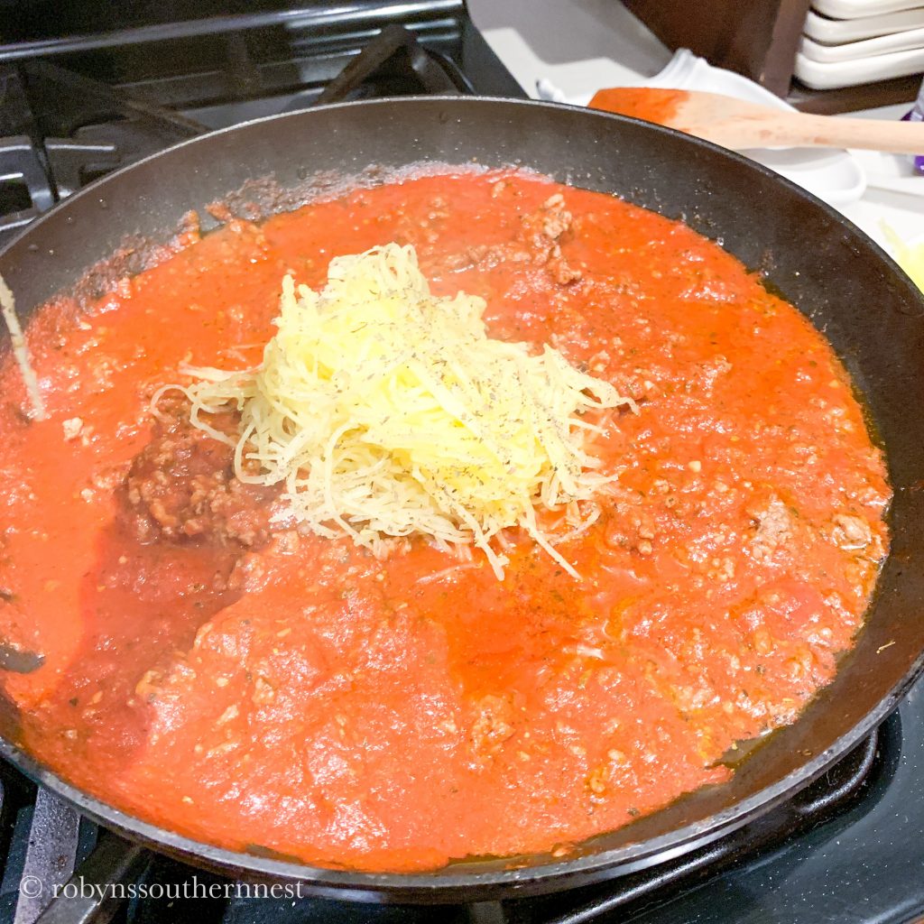 adding the spaghetti squash into the sauce and ground beef 