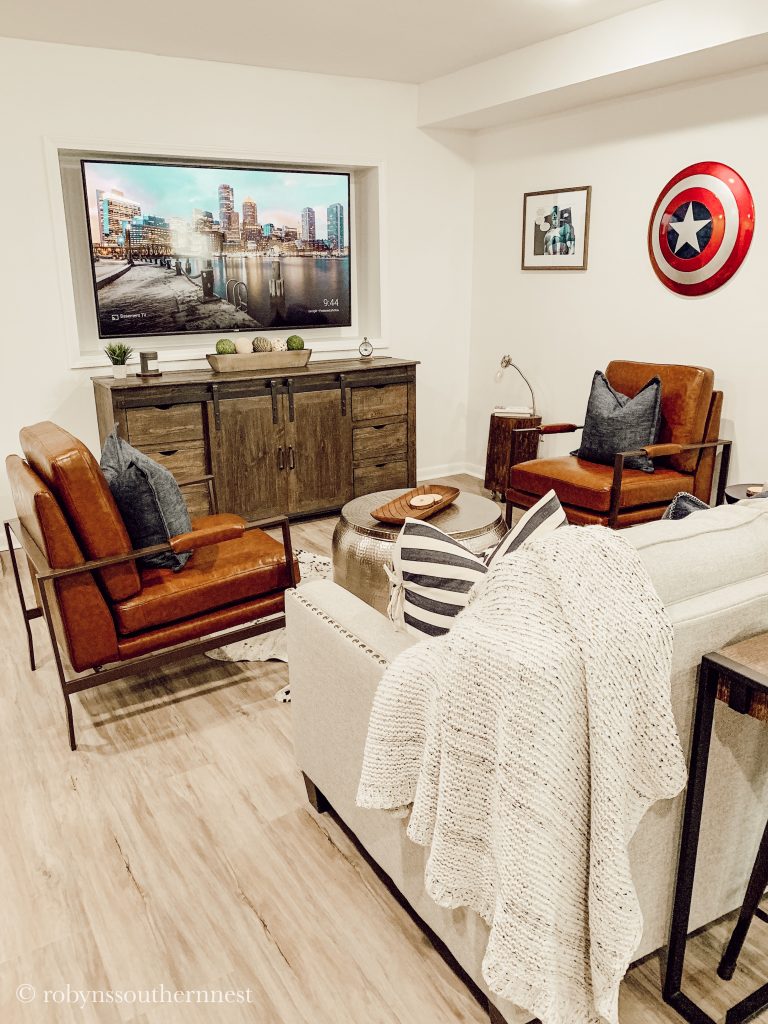 Basement living room with TV and Captain america shield hung on the wall. - Robyn's Southern Nest