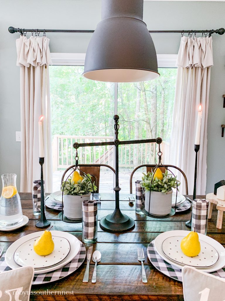 Tablescape with buffalo check napkins and chargers topped with pears